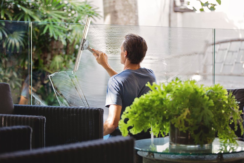Glasbewasser reinigt een raam met een trekker
