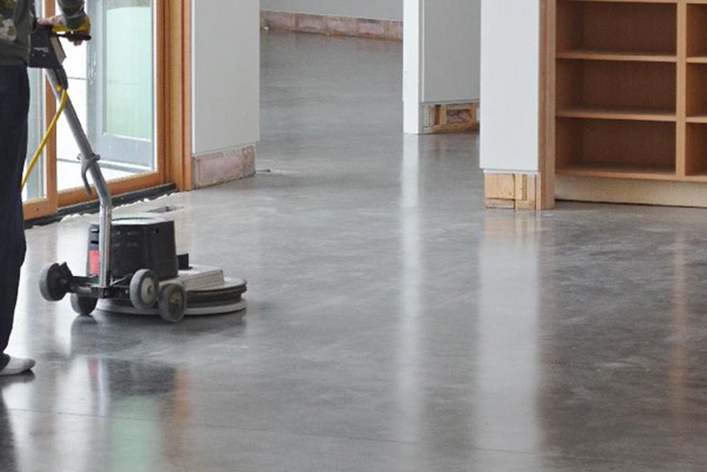 Medewerker reinigt een grote betonvloer machinaal met een schrobmachine