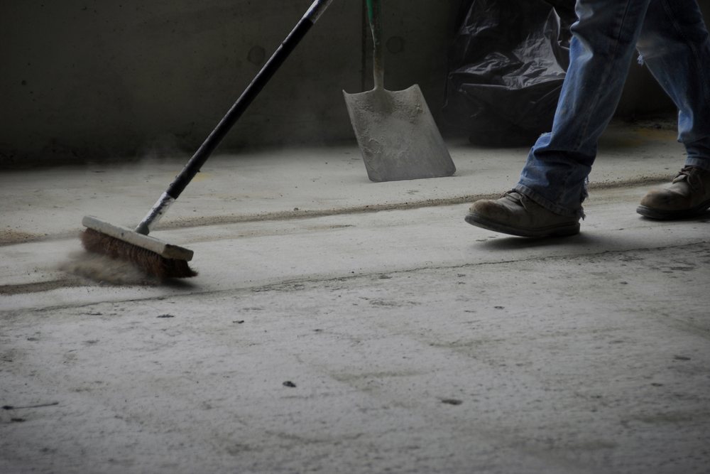 Werfvloer wordt met borstel en schop opgeruimd tijdens de werfopkuis